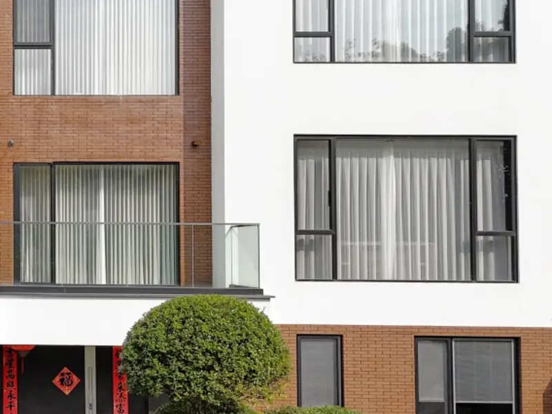 Casement windows and a glass balcony guardrail on a brick and white building facade
