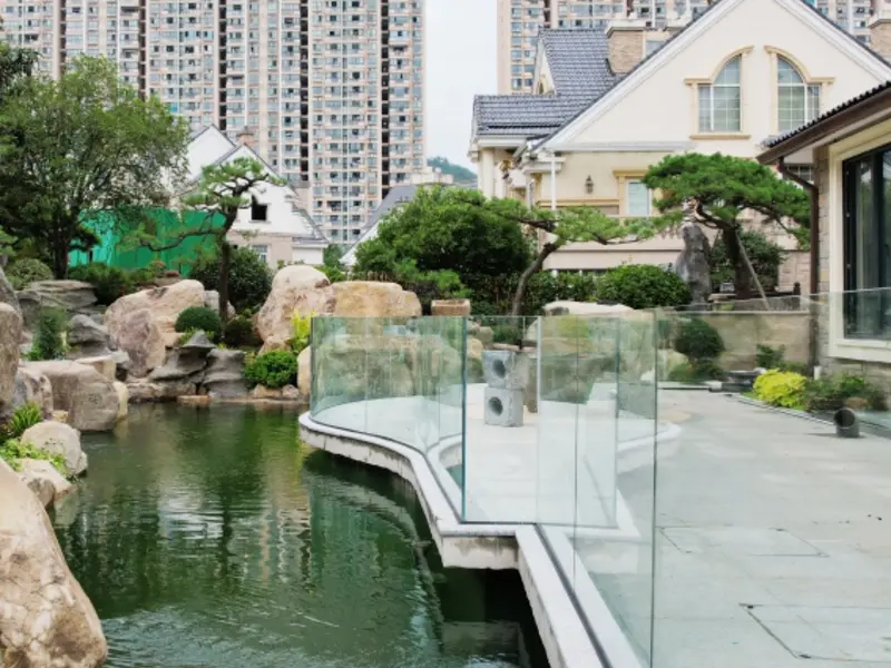 Frameless glass balustrade beside a garden pond
