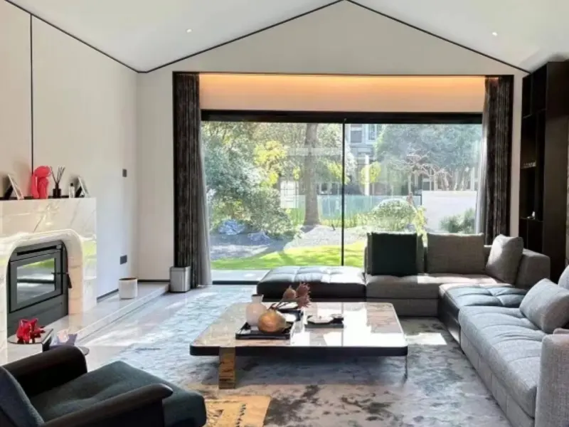 Non-thermal-break sliding door open from a vaulted-ceiling living room to a garden