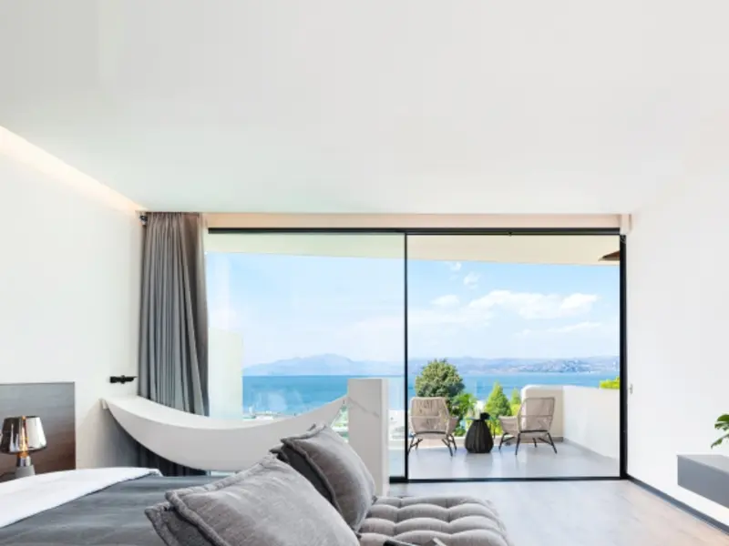 Aluminium sliding door open from a bedroom onto a sea-view balcony